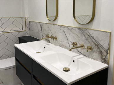 new gold taps installed in a luxury bathroom with black and white sink and marble wall